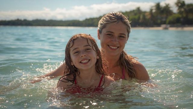 Mother and daughter smiling and wading in turquoise shallow sea on tropical beach