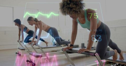 Group practicing pilates reformer while wearable trackers monitoring heart rate and vitals