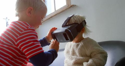 Excited siblings exploring virtual reality worlds together indoors