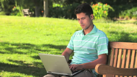 Man Working on Laptop in Sunny Park Environment