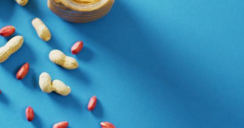 Peanut Butter Jar With Peanuts on Bright Blue Background