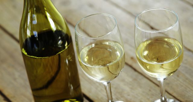 Close up of two glasses and bottle of wine with copy space on wooden background. Wine, alcohol, alcoholic drinks and drinking concept.