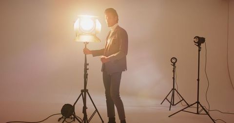Asian adult male adjusting spotlight in professional studio setting