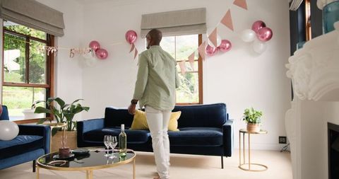 Man Arranging Birthday Decorations in Modern Living Room
