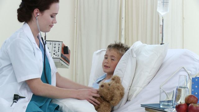 Footage in high definition of beautiful doctor talking and playing with a little boy recovering in hospital. Concept of healthcare