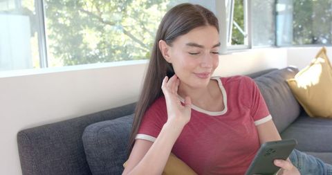Smiling Teen Girl Relaxing at Home with Smartphone