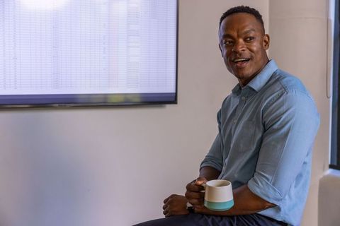 Professional Man with Mug near Data Screen in Modern Office