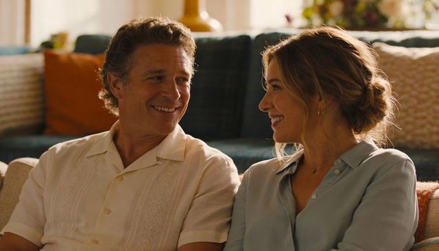 Smiling couple sitting on sofa sharing intimate sunlit moment in cozy living room