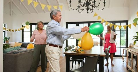 Senior Friends Preparing Birthday Decorations in Living Room