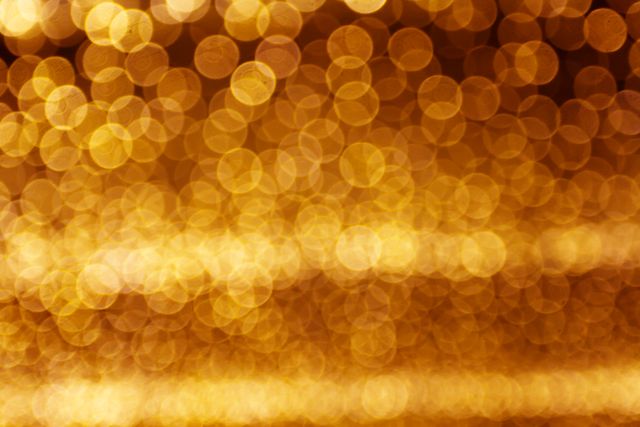 Golden bokeh composing delicate, shimmering background. Ideal for festive and celebratory projects, online content reflecting luxury and elegance, holiday-themed materials, and creative designs requiring vibrant and glowing visuals.