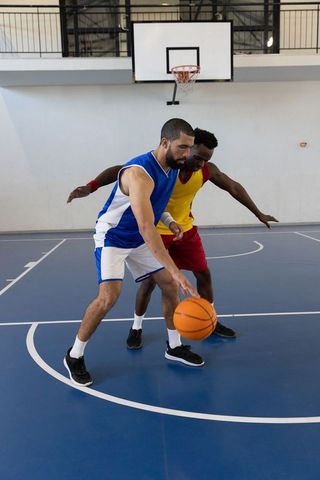 Male Athletes Competitively Playing Basketball on Indoor Court