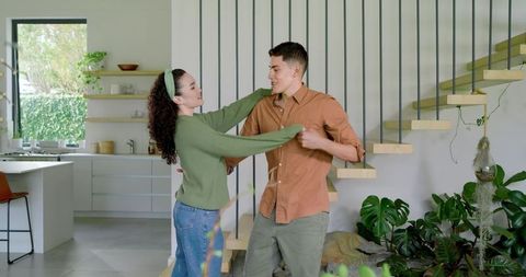 Young Couple Enjoying Dance Near Staircase in Modern Elegant Home