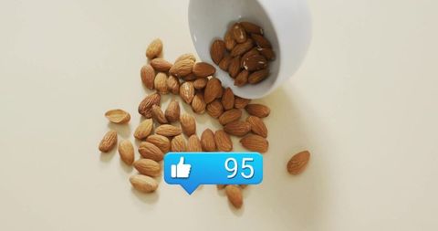 Scattered almonds with social media like icon on cream background