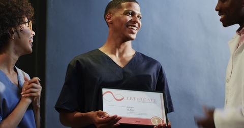 Young professional holding certificate with celebrating colleagues