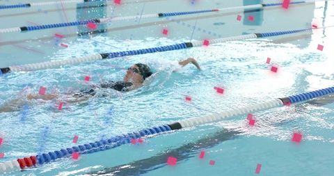 Backstroke swimmer training in indoor lap pool splashing through lane dividers with goggles