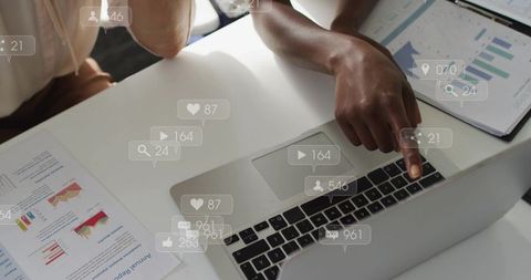 Two professionals pointing at laptop reviewing analytics reports with social media metric overlays