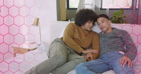 Two men cuddling on bed in bright cozy bedroom, intimate relaxed couple moment
