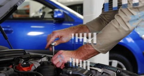 Mechanic tightening engine bolt with ratchet during car maintenance next to blue vehicle