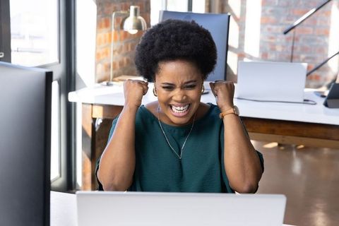 Excited Businesswoman Celebrating Success at Office Desk