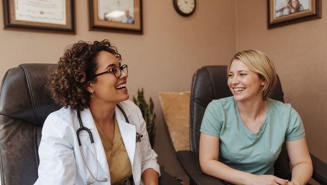 Smiling clinician and patient laughing during relaxed primary care consultation