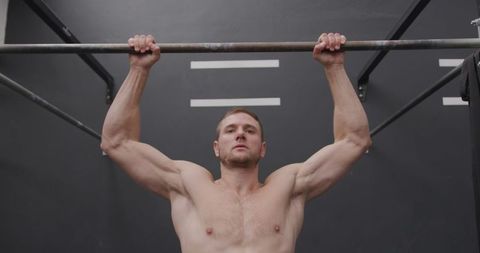 Athletic Man Performing Chin Ups in Gym Building Strength