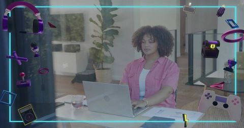 Woman typing on laptop with neon gaming icons overlay for remote tech and creative work