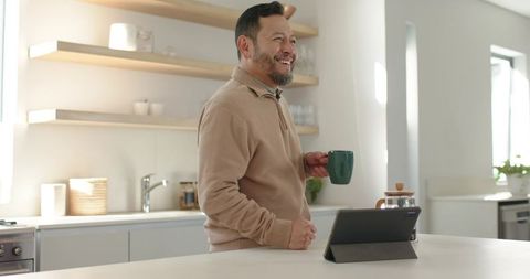 Mature Man Enjoying Coffee and Tablet in Minimalist Kitchen