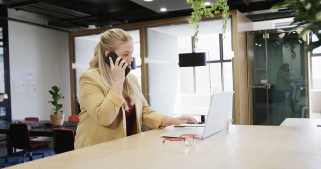 Young Professional Woman Working in Modern Office, Talking on Phone and Using Laptop - Download Free Stock Images Pikwizard.com