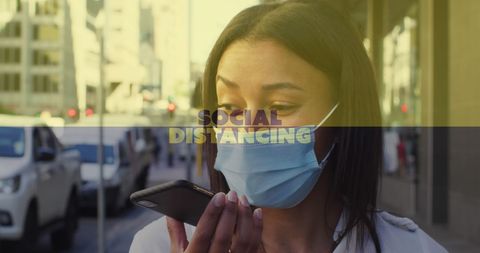 Woman wearing face mask engages in conversation through smartphone while walking on city street. Useful for illustrating COVID-19 safety measures, modern communication, pandemic lifestyle adaptations, and urban scenes during health crises. Can be utilized in healthcare communications, city lifestyle features, pandemic safety guidelines, and telephone service promotions.