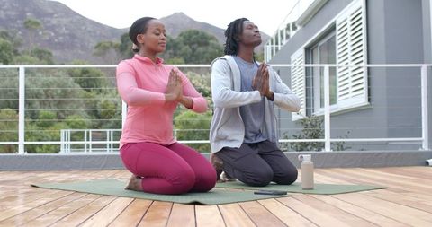 Couple Practicing Yoga Kneeling in Prayer Pose on Rooftop for Mindfulness and Wellness