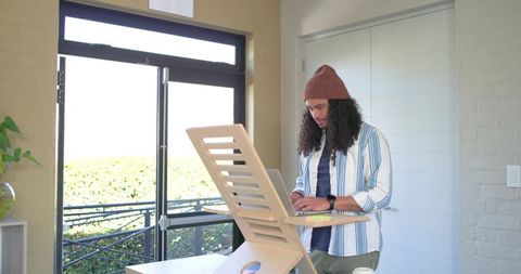 Mid-adult man working at standing laptop riser in bright minimalist home office