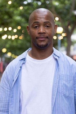 Confident african american man wearing casual shirt and silver chain, evening urban bokeh