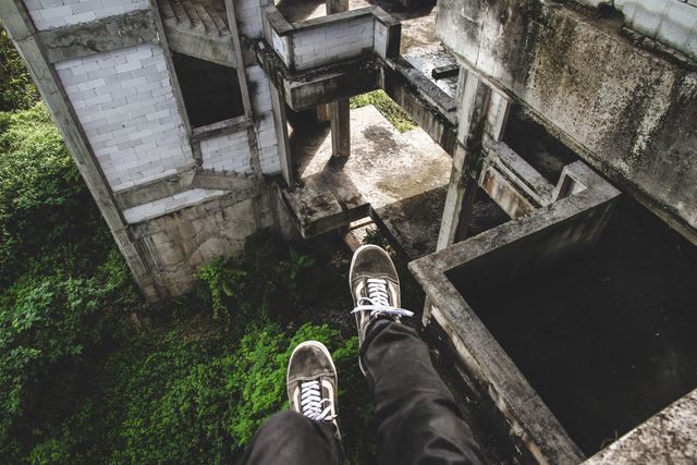 Person Sitting on Edge of Abandoned Building Soaring Above Trees - Download Free Stock Photos Pikwizard.com
