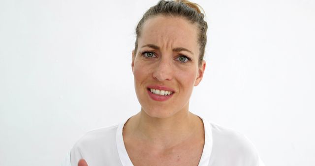 Woman with confused expression looking directly ahead, set against a white background. Suitable for use in articles or presentations related to emotions, decision-making, confusion, or mental health topics. Can be used for advertising services such as therapy, counseling, or self-help resources.