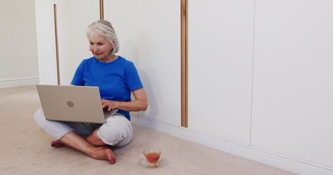 Senior Woman Relaxing at Home with Laptop and Tea