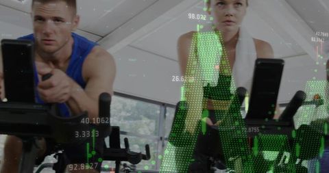 Two cyclists pedaling indoor spin bikes with green fitness hud overlay in bright gym