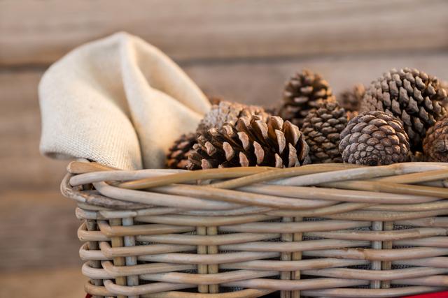 Pine cones in wicker basket on wooden plank during christmas time