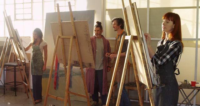 Art students painting on easels in a well-lit studio. Perfect for depicting creativity, learning environments, art education, and artistic expression. Useful for promoting art schools, workshops, or educational programs.