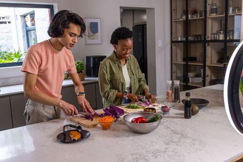 Diverse pair chopping colorful vegetables on marble kitchen island during cooking collaboration