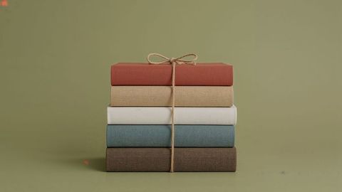 Stack of hardcover books tied with twine against olive background