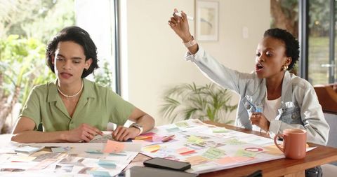 Multiracial Team Brainstorming and Planning with Sticky Notes at Daylit Wooden Table