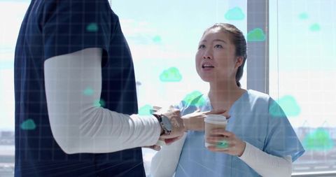 Clinician Talking with Colleague Holding Coffee in Scrubs with Cloud Data Overlay