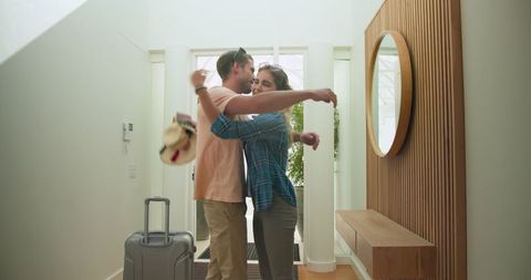 Joyful Homecoming, Couple Embracing with Luggage at Entrance