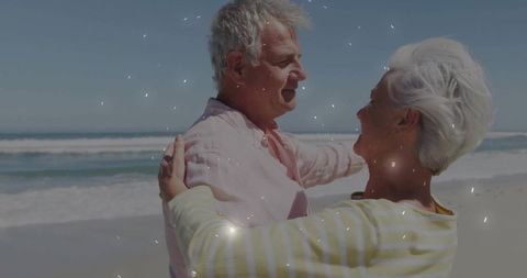 Senior couple embracing on beach under sun light