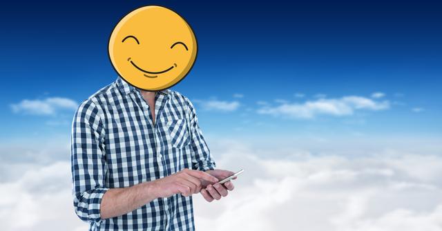 Digital composite of Man with emoji over face using smart phone in sky
