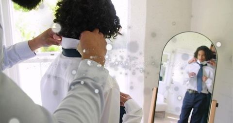Father adjusting son's tie in mirror before formal event, morning bonding and dressing ritual