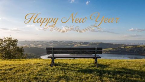 Wooden bench overlooking lake and rolling hills at golden sunrise with happy new year text