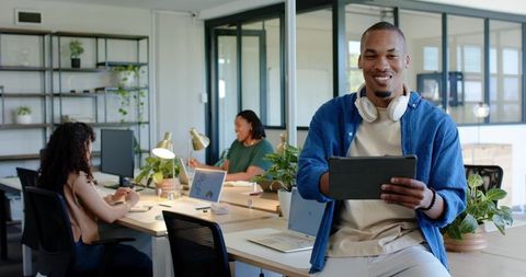 African professionals collaborating in modern open-plan office using tablet and laptops