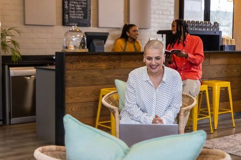 Working remotely in modern cafe with smiling diverse team chatting behind counter
