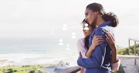 Mother and daughter embracing on scenic seaside balcony
